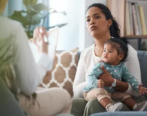 Post Adoption Contact - Picture of a guardian with a child on their knee in consultation with a post adoption contact specialist.