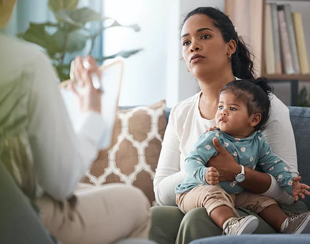 Post Adoption Contact - Picture of a guardian with a child on their knee in consultation with a post adoption contact specialist.